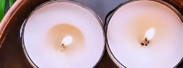 Two candles floating in a wooden bowl